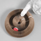 Cat playing with the ball in the cardboard scratcher groove